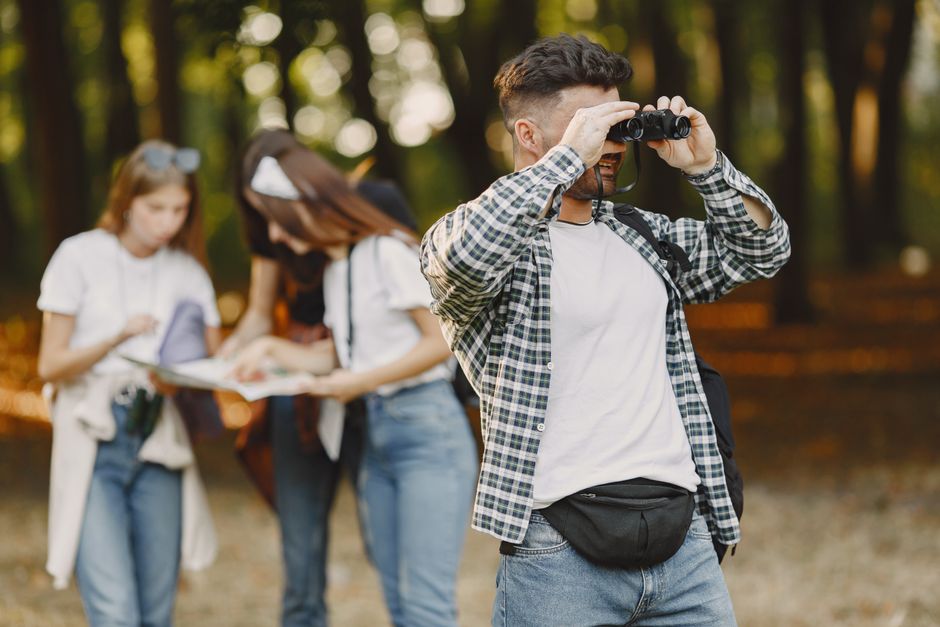 A group of friends enjoys a day outdoors, exploring with binoculars and a map.